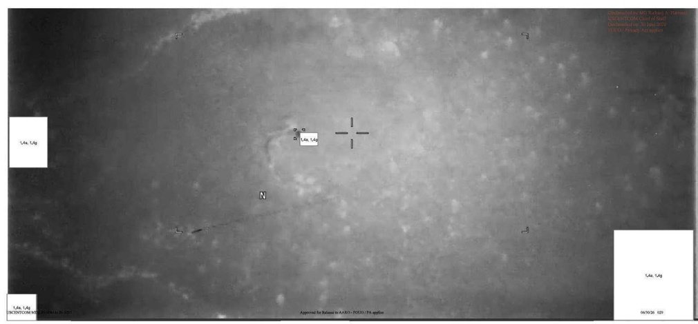Imagem de sensor em tons de cinza mostrando terreno visto do alto, com retículo de mira no centro e retângulos brancos de tarja.