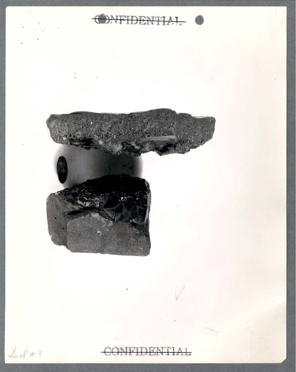 Fotografia em preto e branco de dois blocos escuros e irregulares de material poroso, com a palavra Confidential riscada no alto e embaixo.