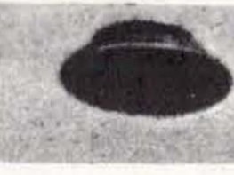 Fotografia antiga de jornal mostrando um objeto escuro em forma de disco contra o céu claro.