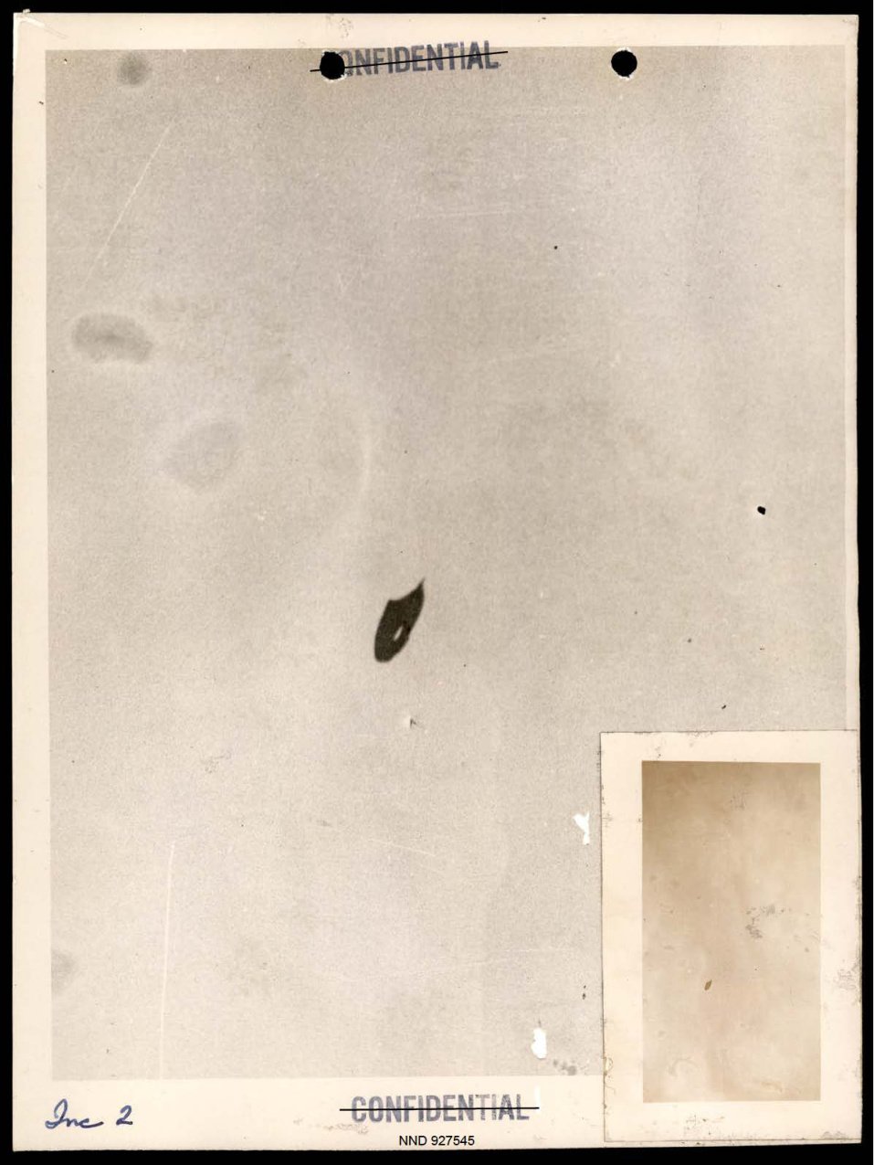 Fotografia desbotada de céu claro com uma pequena forma escura no centro e uma cópia menor da foto colada no canto.
